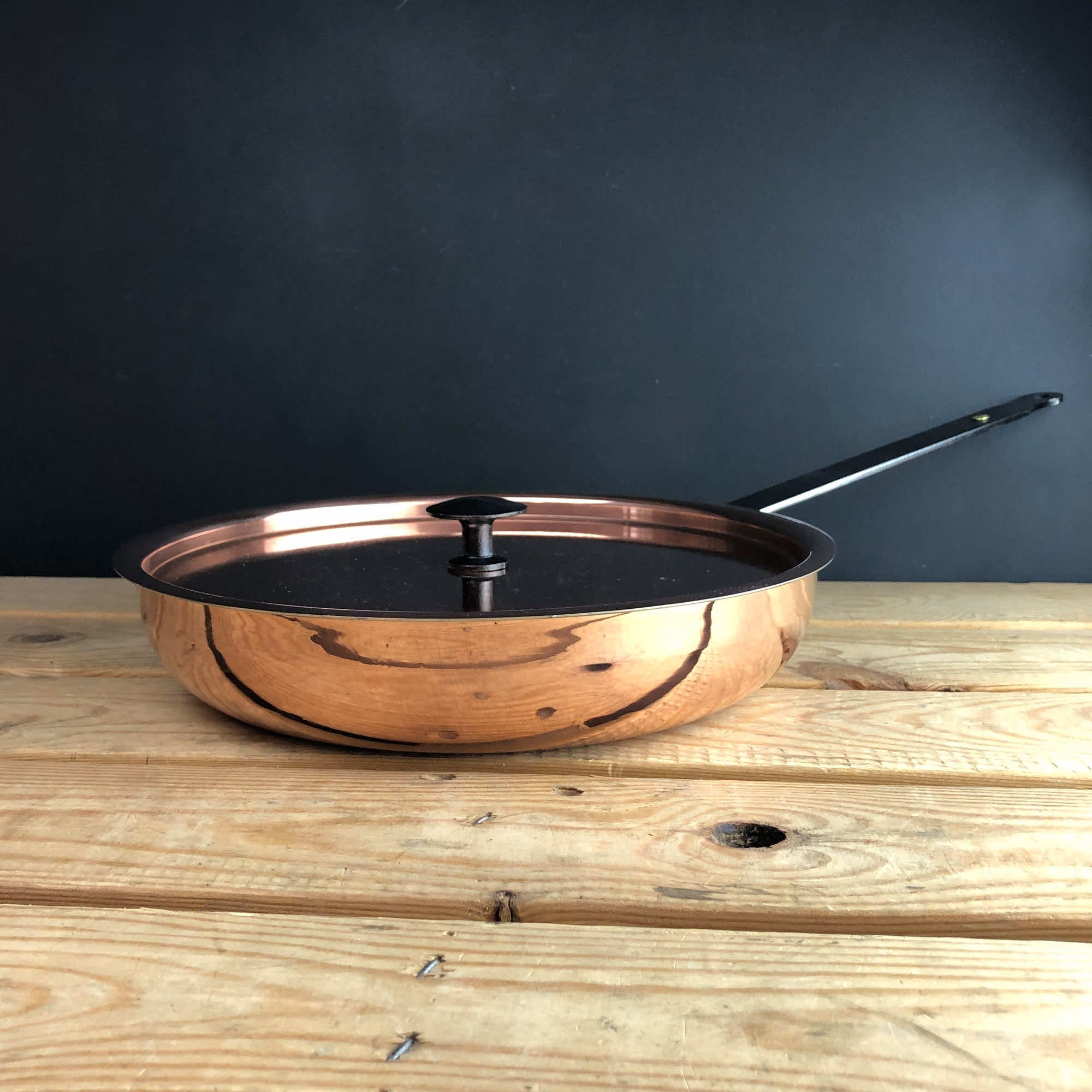 Copper frying pan with lid on table