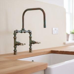 Vintage-style kitchen faucet with wooden countertop and white wall