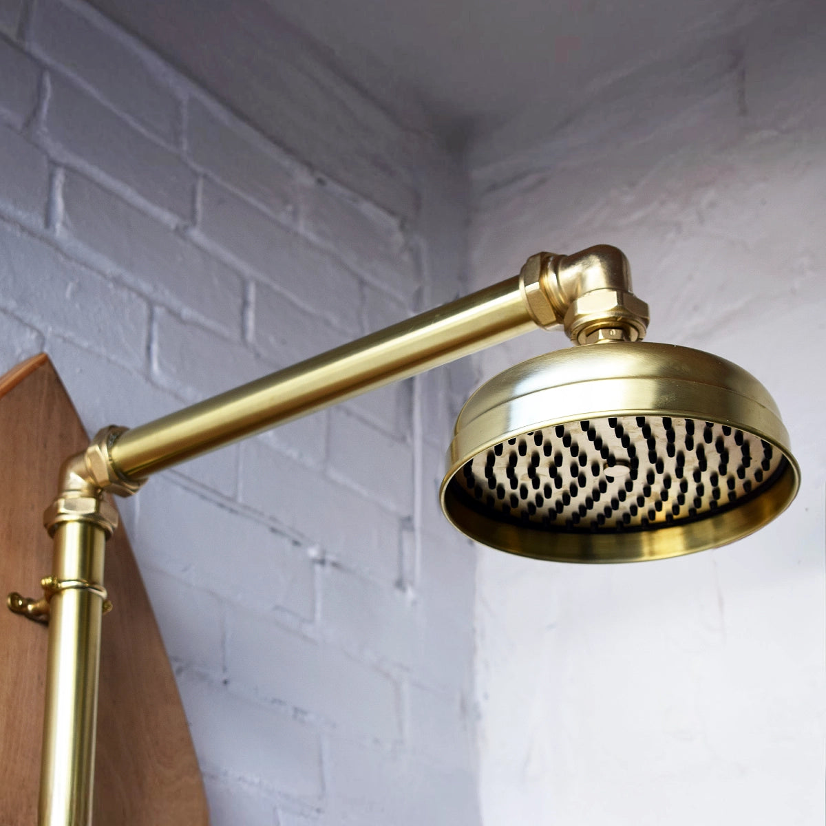 Closeup of brass shower on wood surfboard