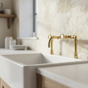 Kitchen sink with brass faucet against a textured wall