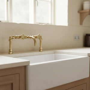 White kitchen sink with brass faucet in a bright room