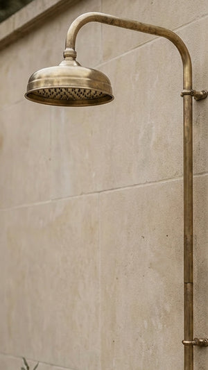 Brass shower head and hose mounted on a tiled wall
