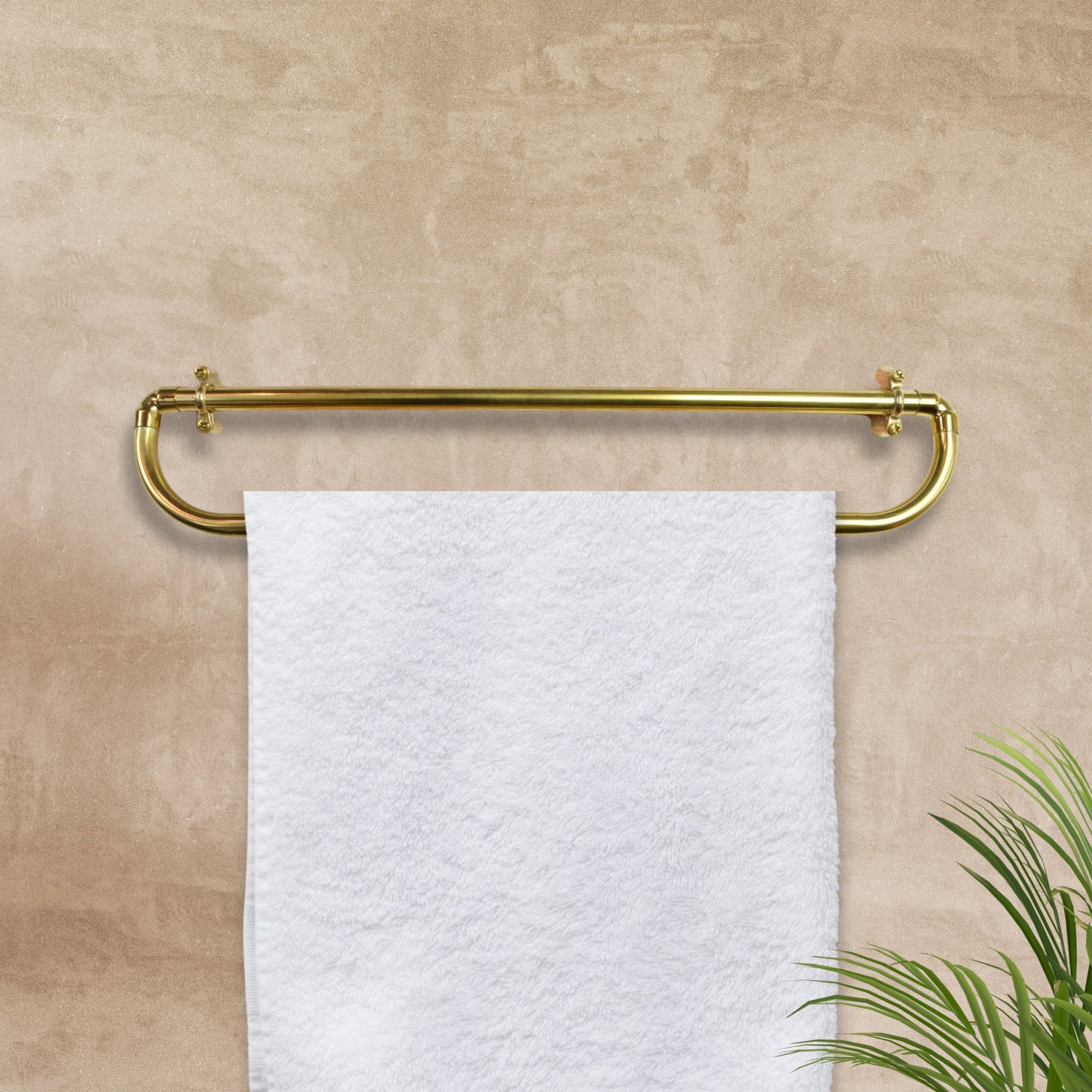 brass towel rack with a white towel on a beige wall luxury towel rail