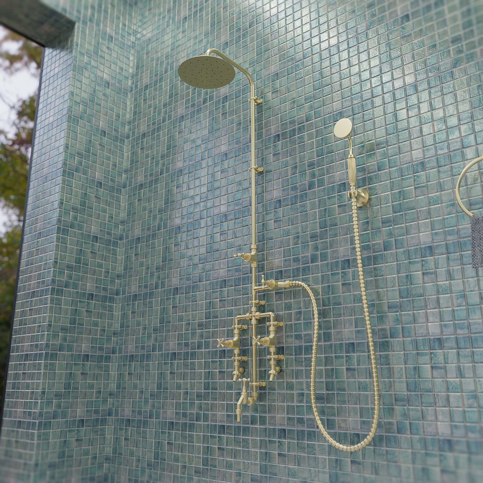 Brass seducto shower in bathroom on blue tiles