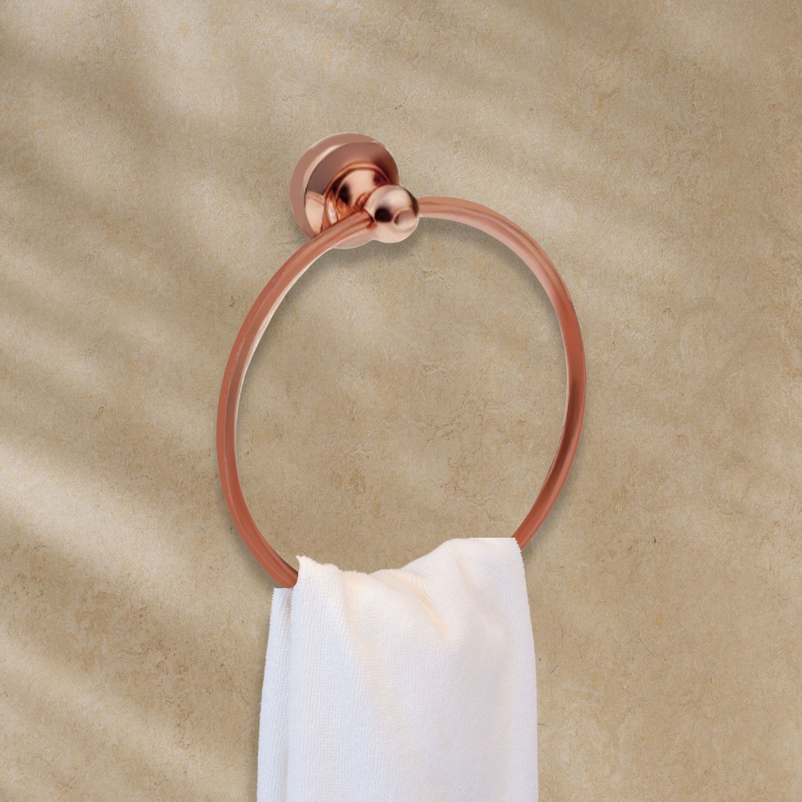 copper towel ring with a white towel on a beige wall
