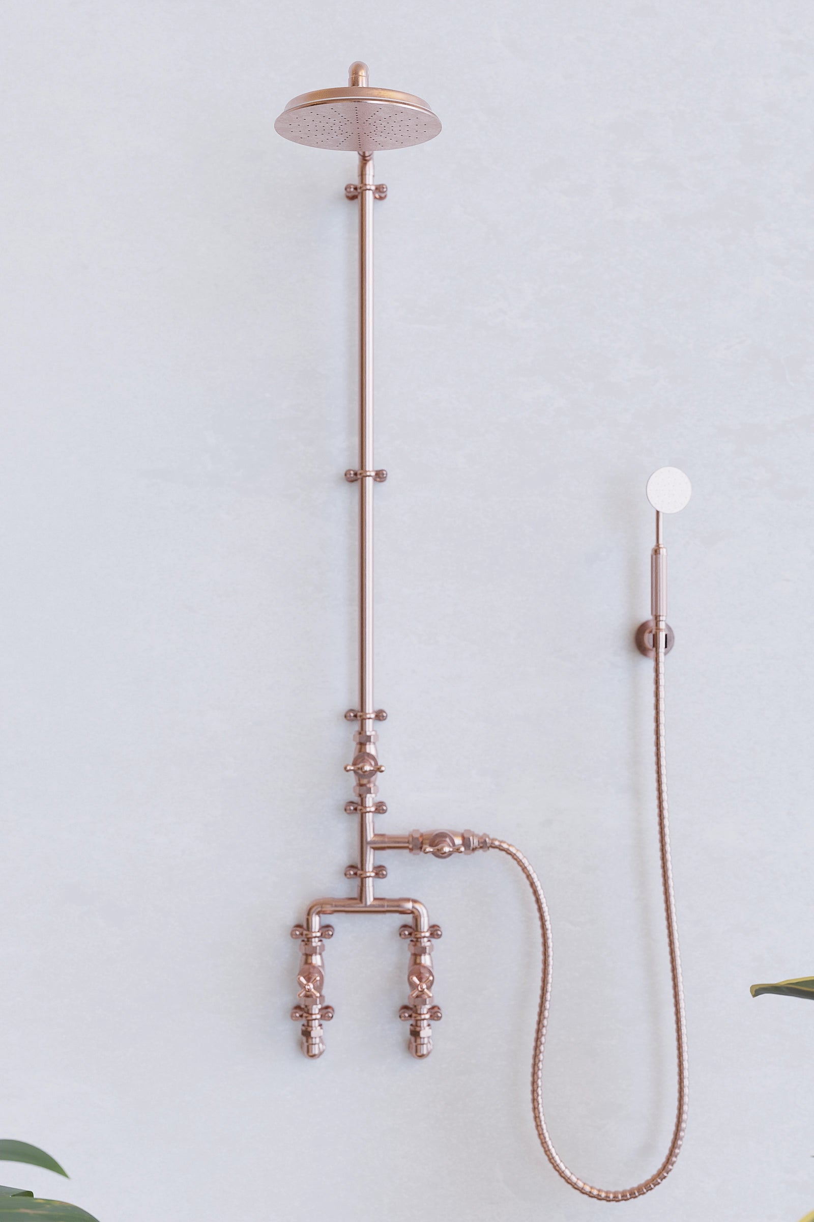 Copper shower on white backdrop with plants