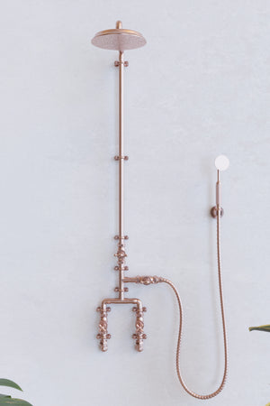 Copper shower on white backdrop with plants