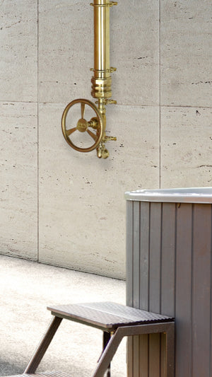 brass cold shower bold architectural shower design photographed next to a hot tub, Jacuzzi.