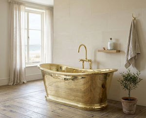 brass freestanding bathtub in a bathroom with a window and plant.