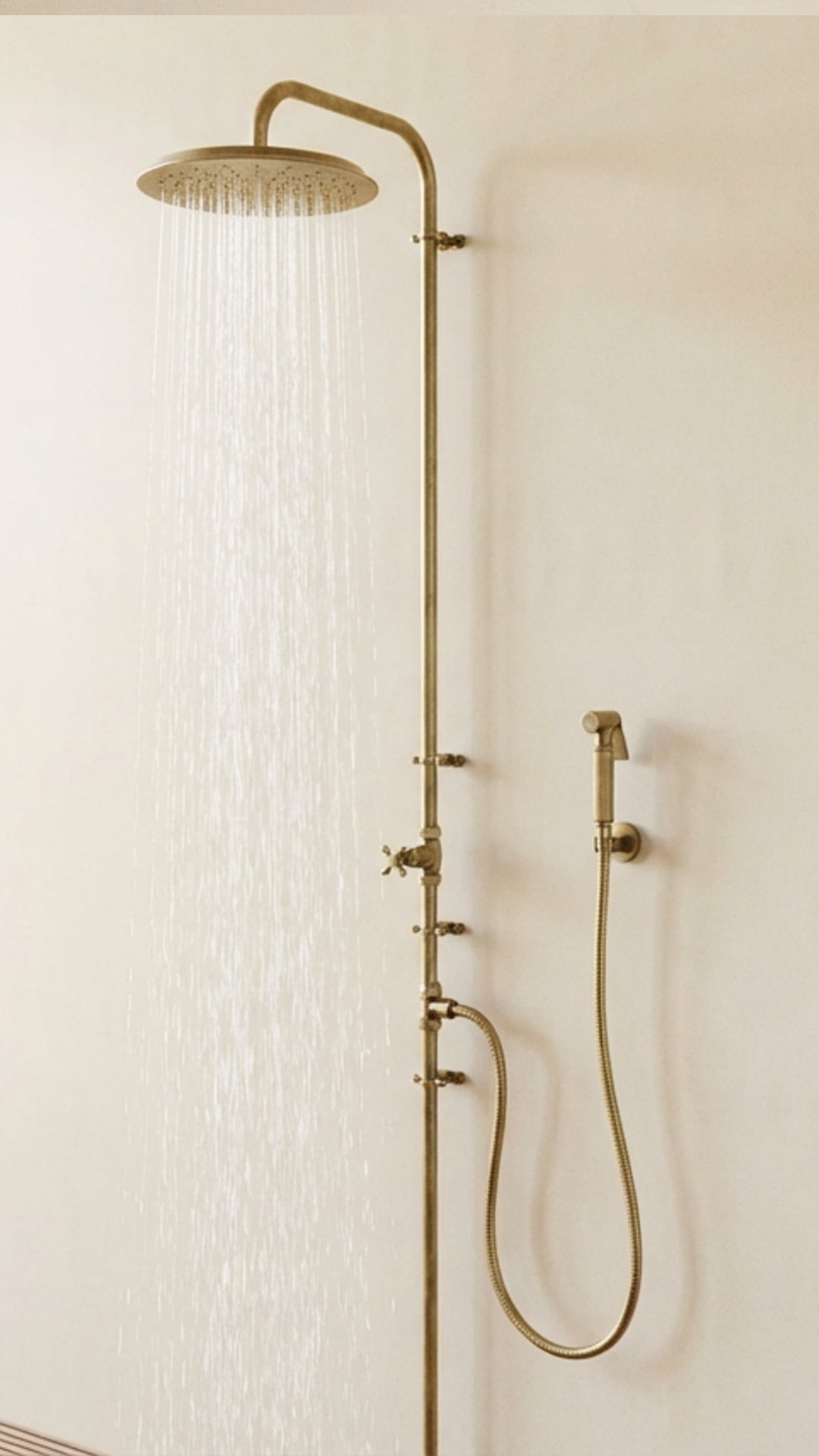 Brass shower system with rain shower head and handheld shower on a white wall.