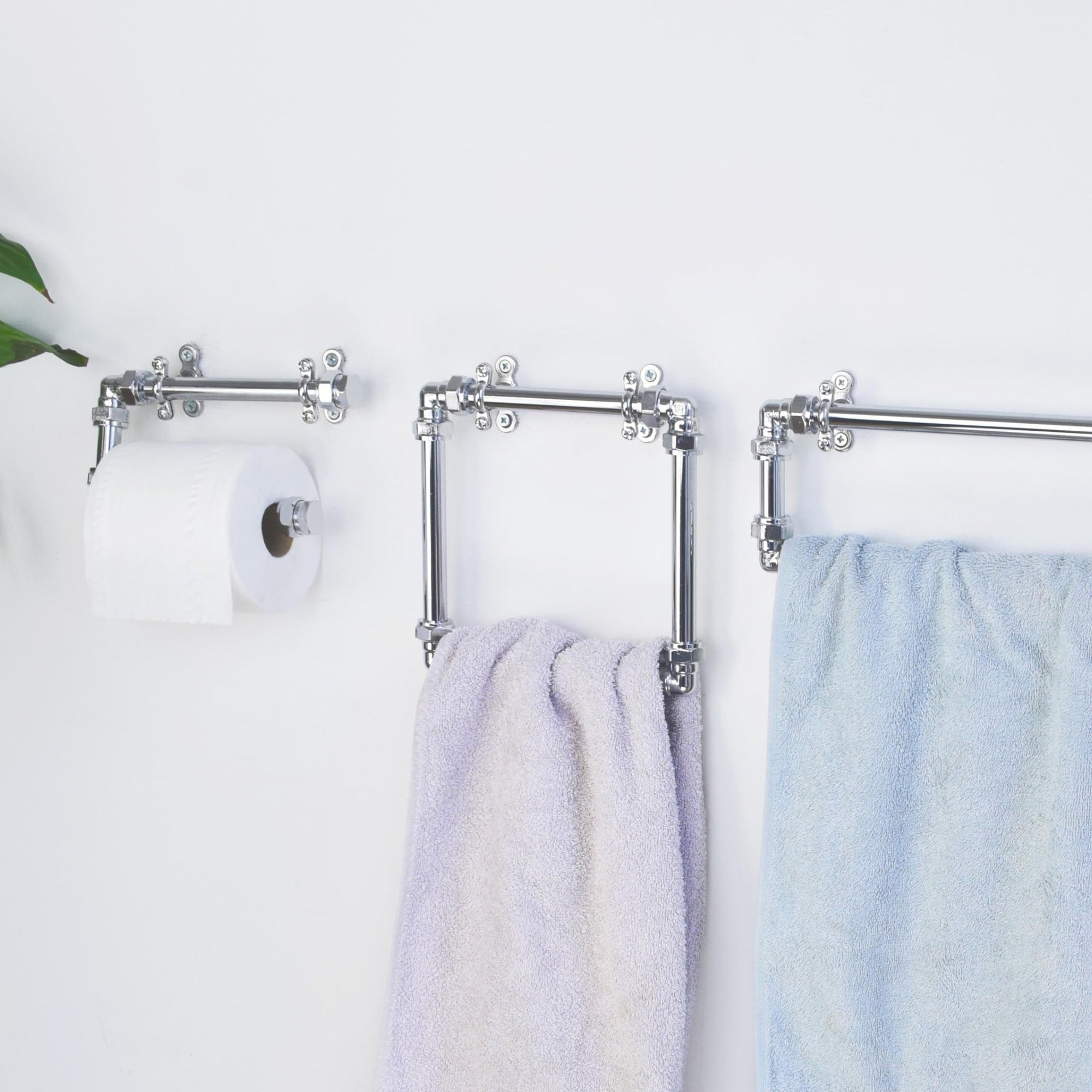 Bathroom towel rack with towels and toilet paper holder on a white wall.