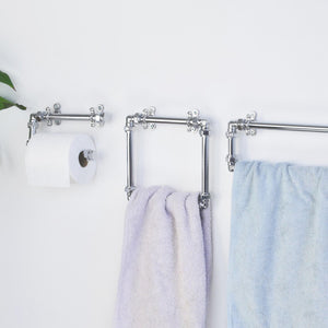 Bathroom towel rack with towels and toilet paper holder on a white wall.