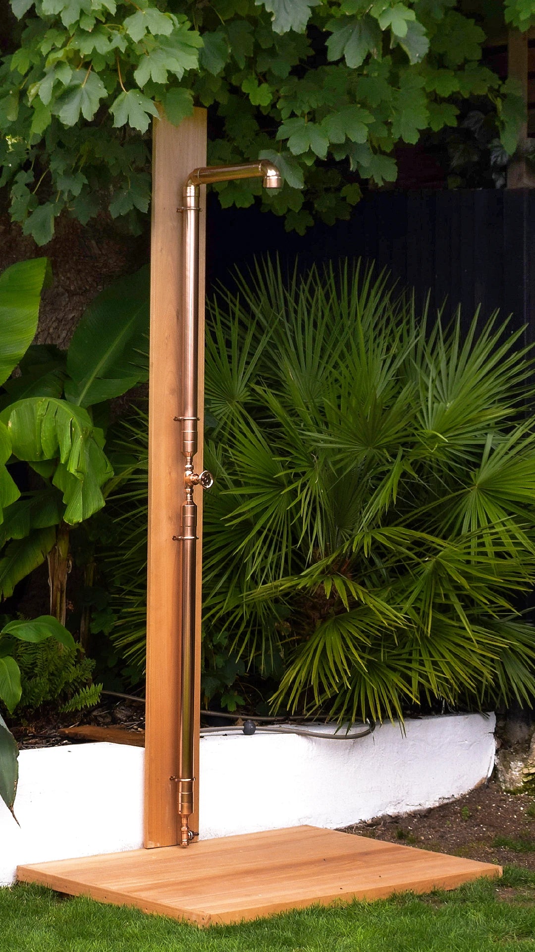 copper shower on surf board with green foliage backdrop 