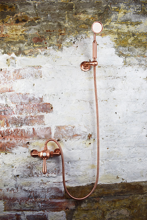 copper mixer shower with handheld shower on brick wall