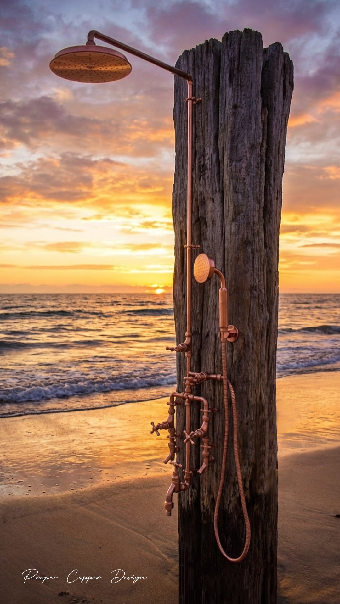 Copper shower head and fixtures attached to a wooden post on a beach at sunset.