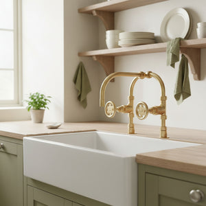 Modern kitchen with a white sink and gold faucet, wooden shelves with plates and bowls.