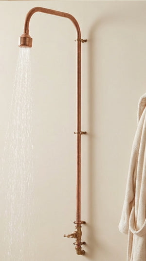 Rustic copper shower head and control panel mounted on a beige wall.