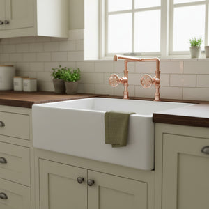 Modern kitchen with a white farmhouse sink, copper faucet, and wooden countertops.