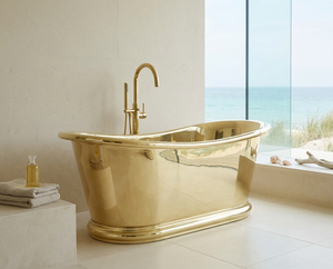 brass freestanding bathtub in a bathroom with a view of the ocean.