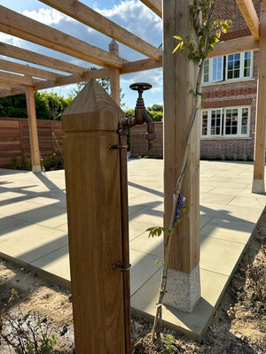Wooden garden feature with a tree and building in the background