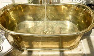 brass bathtub with water flowing into it on a reflective surface