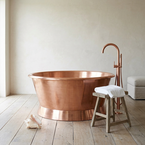 Copper bathtub with faucet and stool in a bathroom setting