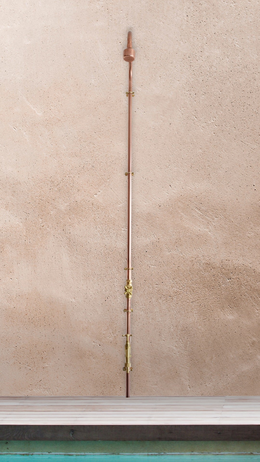 copper garden shower photographed next to a swimming pool