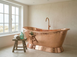 Copper bathtub in a bathroom with a window and stool.