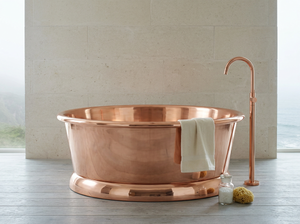 Copper bathtub with a towel and accessories in a bathroom setting
