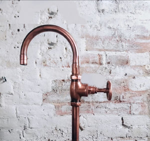 Copper faucet against a textured white brick wall