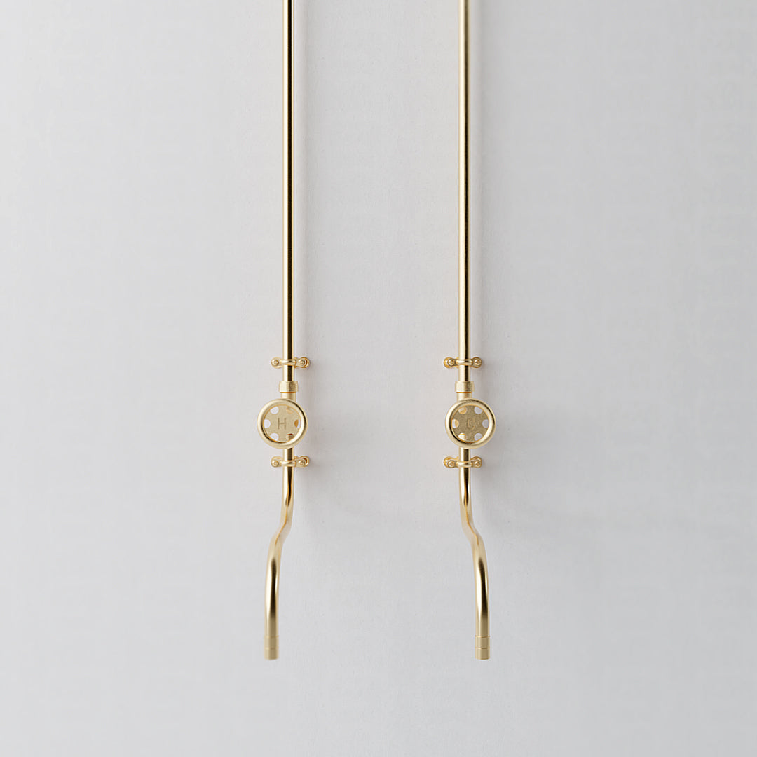 Full length brass tap mounted on white wall