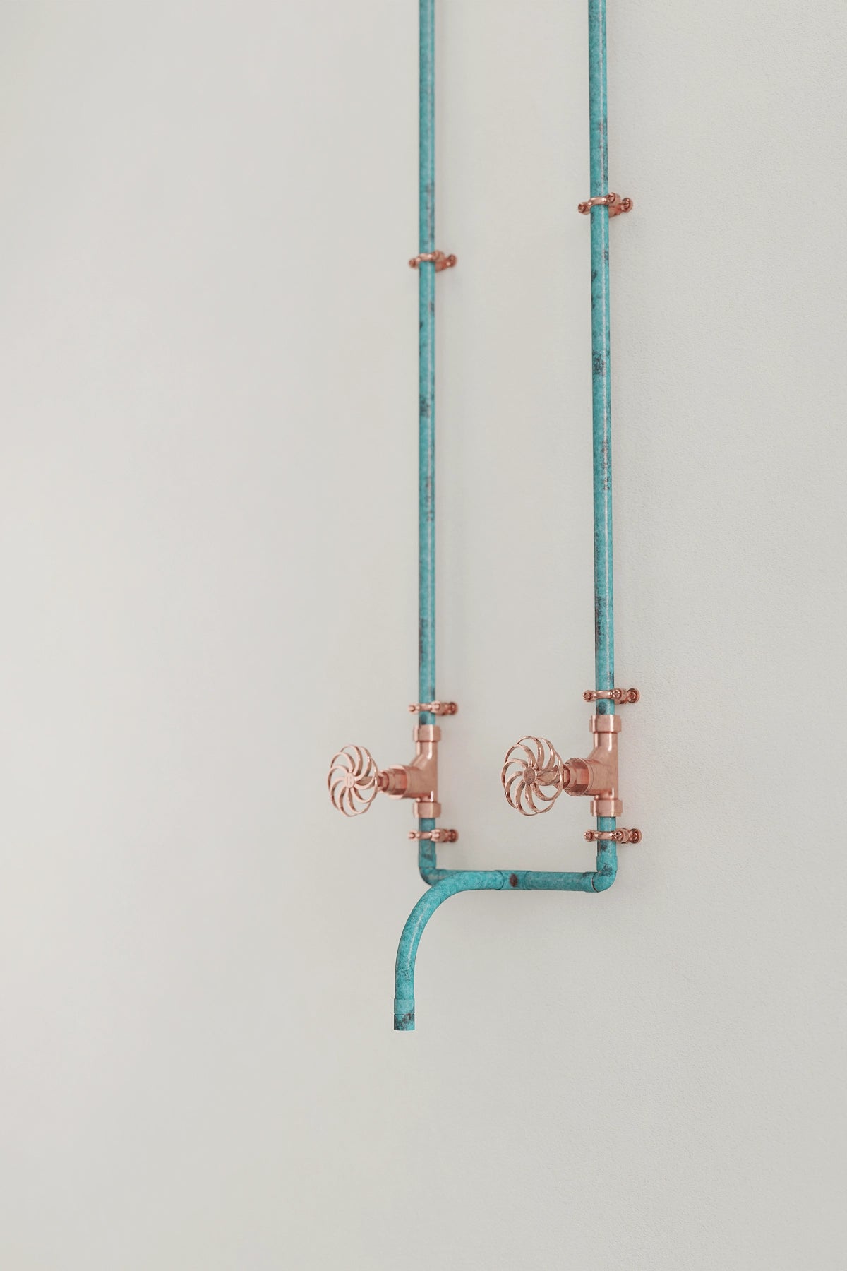 wall-mounted verdigris tap on white wall angled 