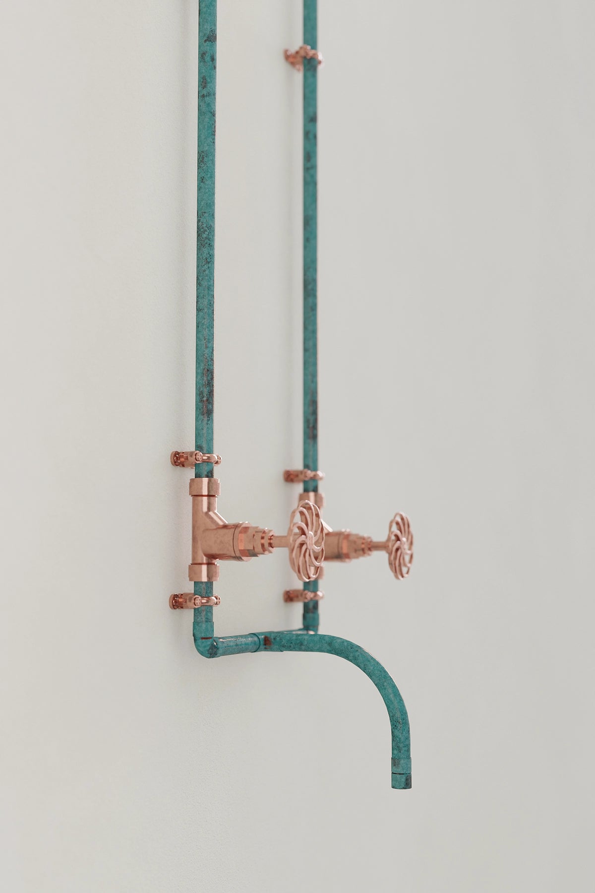 wall-mounted verdigris tap on white wall angled 