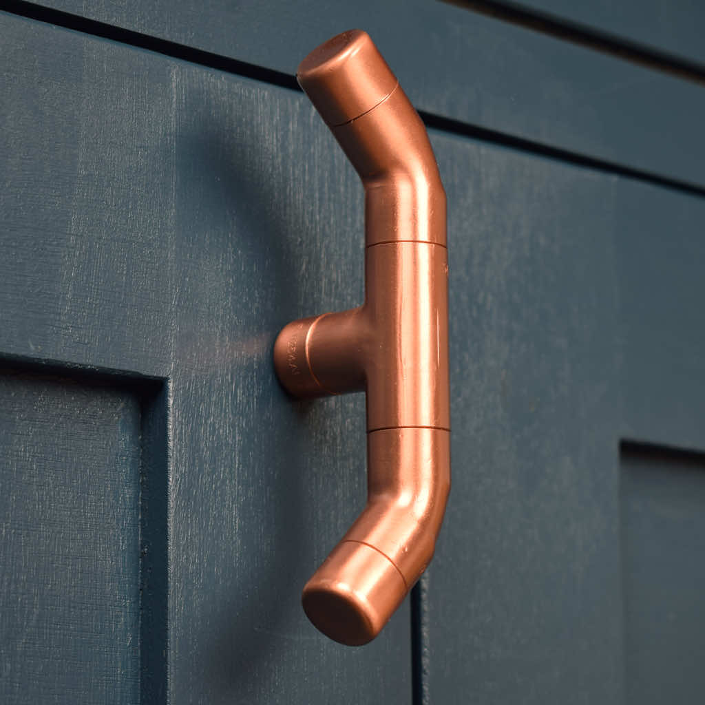 Curved Copper Handle on Blue Cabinet Closeup
