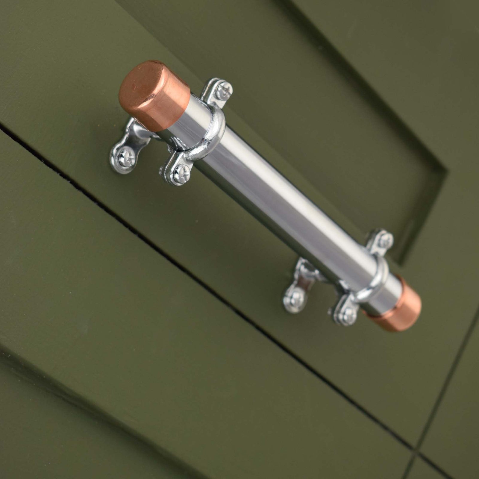 chrome and copper pull with chrome brackets on green kitchen drawers