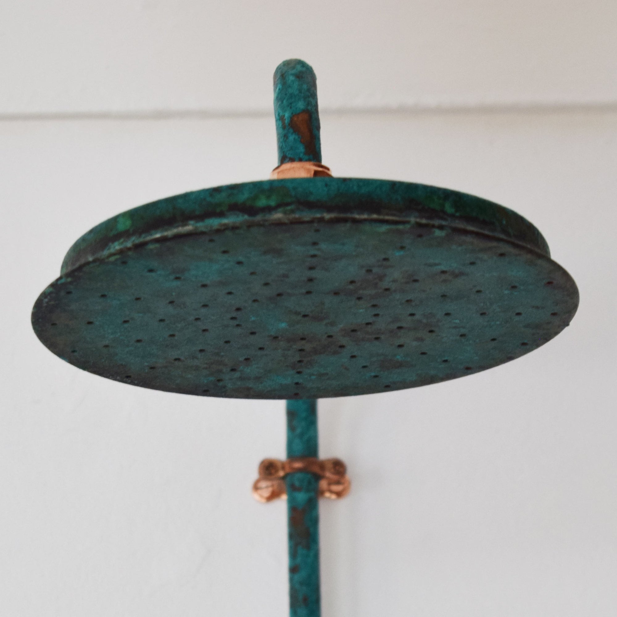 Close up of a verdigris finish shower head with polished copper