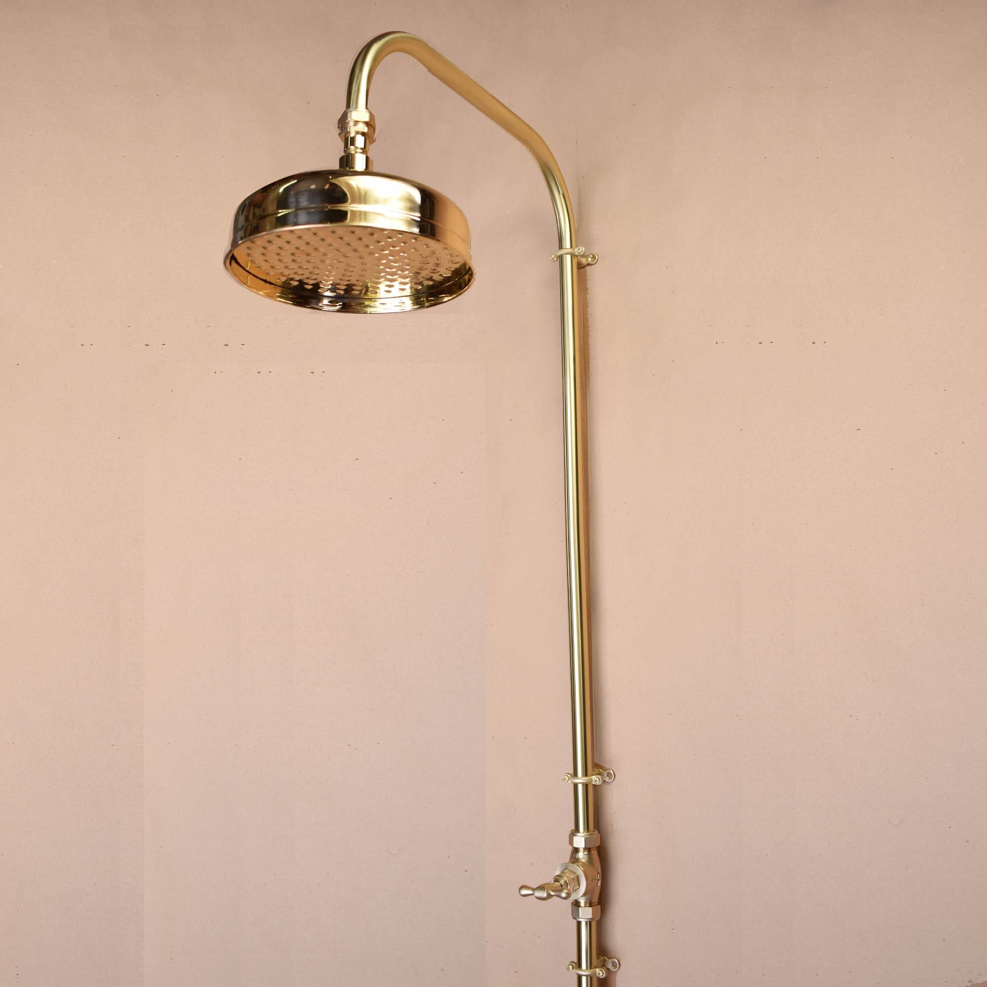 indoor or outdoor brass fixtures, solid brass shower head photographed on a plastered wall