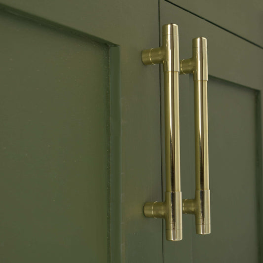 brass handle on green cabinets