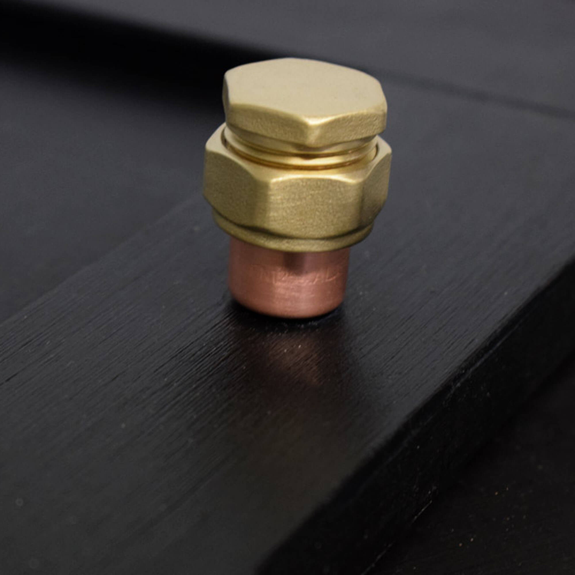 Copper and brass raised knob bolt on black standing
