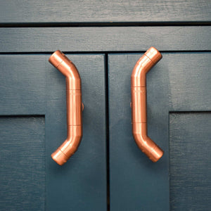 Curved Copper Handle on Blue Cabinet Front Closeup
