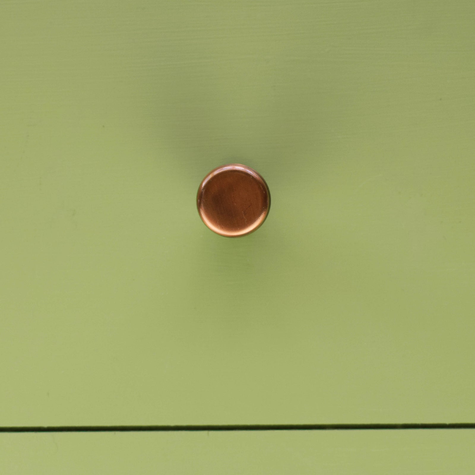 Aged copper cabinet knob on sage green drawer front